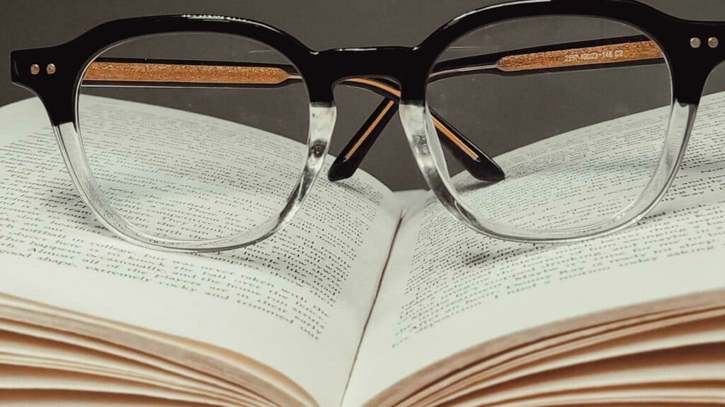 A close up a pair of glasses laying on an open book symbolizing educating yourself in addiction recovery.